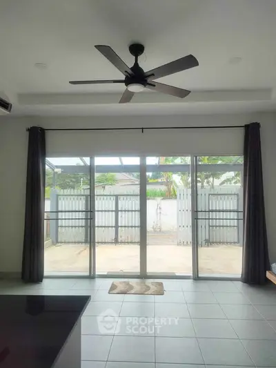 Spacious living room with ceiling fan and large sliding glass doors leading to a private patio.