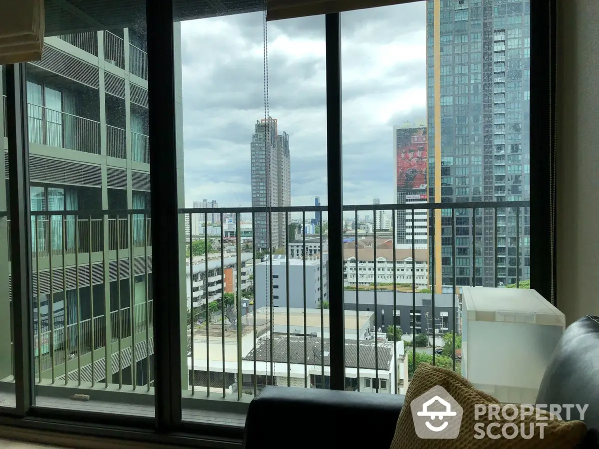 Spacious living room with floor-to-ceiling windows offering an expansive city view, modern furnishings, and abundant natural light.