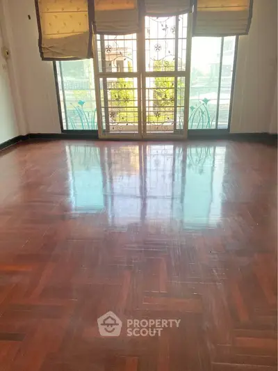 Spacious living room with polished wooden floors and large windows.