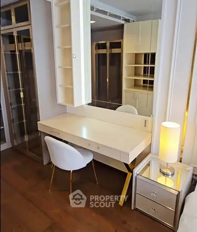 Elegant bedroom with modern vanity and stylish chair, featuring ample storage and warm lighting.