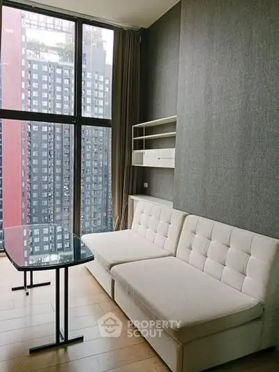 Modern living room with large windows and city view, featuring a stylish sofa and sleek table.