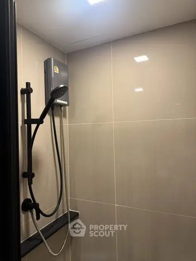 Modern bathroom with sleek showerhead and neutral tiles, perfect for a contemporary home.