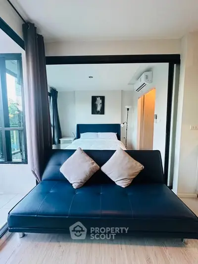 Modern bedroom with stylish sofa and large windows offering natural light.