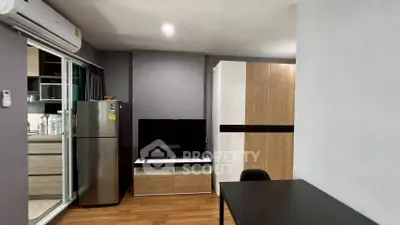 Modern living room with sleek design, featuring a TV, fridge, and stylish furniture in a cozy apartment.