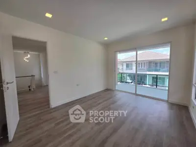 Spacious empty room with large window and wooden flooring in modern home