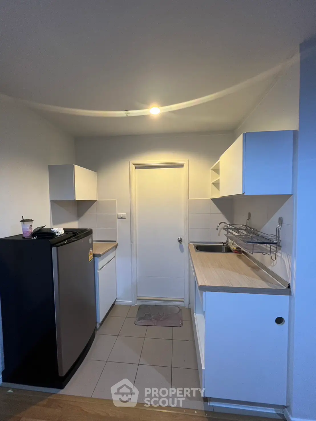Compact kitchen with modern cabinets and mini fridge, ideal for small apartments.