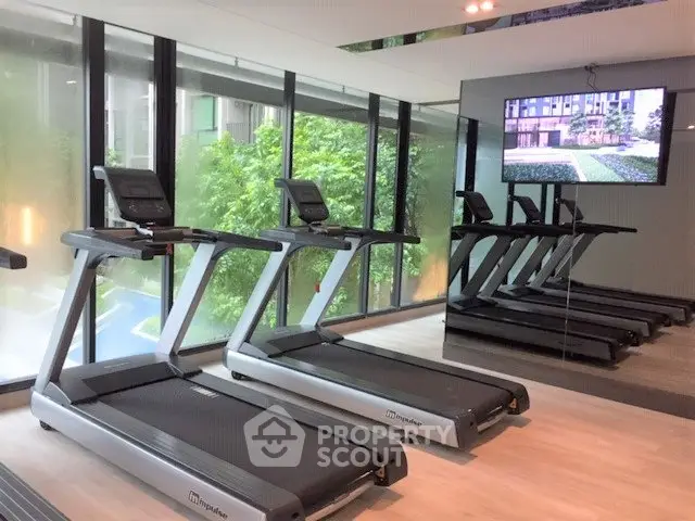 Modern gym with treadmills and large windows in luxury apartment building.