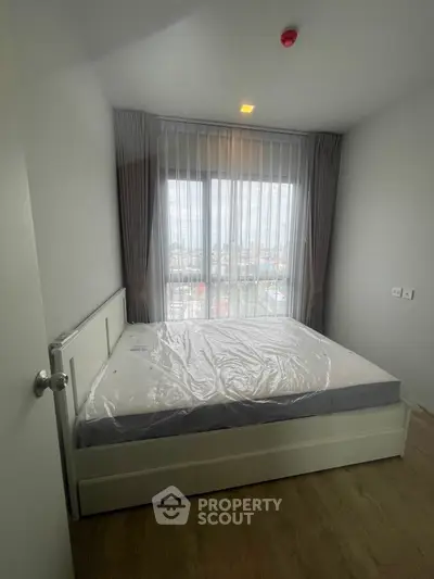 Cozy bedroom with large window and natural light in modern apartment.