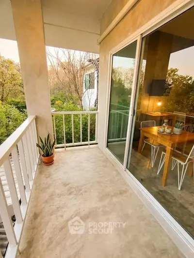 Charming balcony with serene garden view and cozy dining area, perfect for relaxation and entertaining.