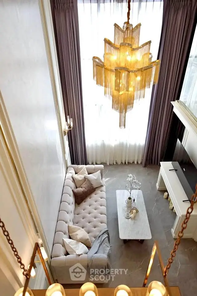 Luxurious living room with high ceiling, elegant chandelier, and plush sofa, perfect for sophisticated living.