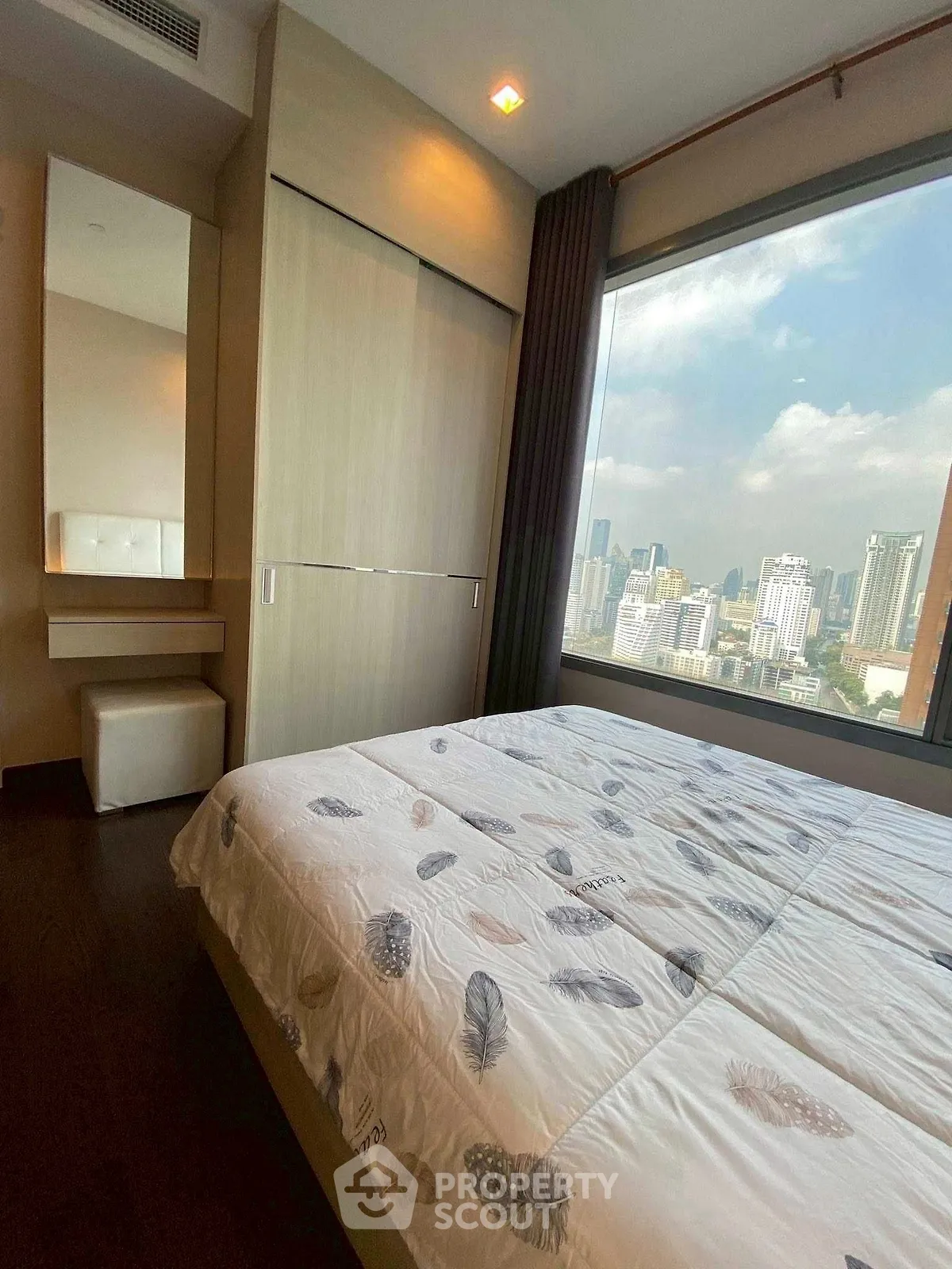 Spacious bedroom with large window offering stunning city views in modern apartment.