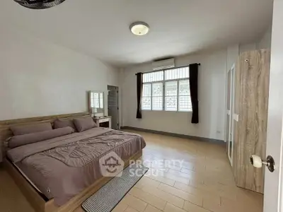 Spacious bedroom with modern decor and large windows for natural light.
