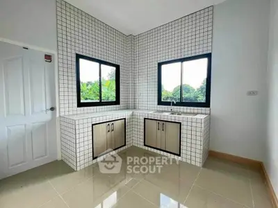 Modern kitchen with tiled walls and large windows offering lush green views.