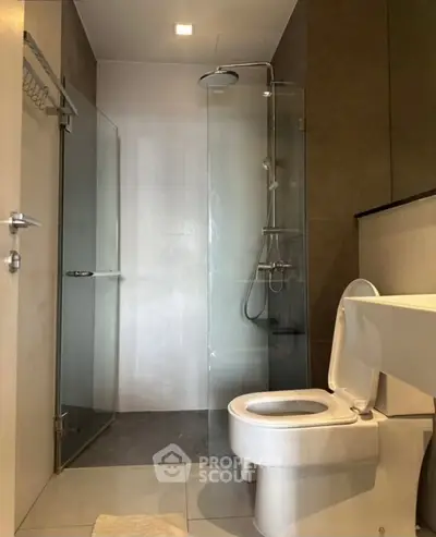 Modern bathroom with glass shower and sleek fixtures in contemporary apartment.