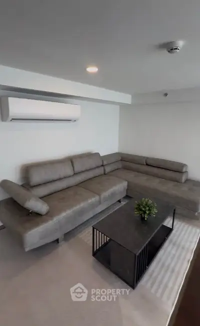 Modern living room with stylish gray sectional sofa and sleek coffee table, perfect for relaxation.