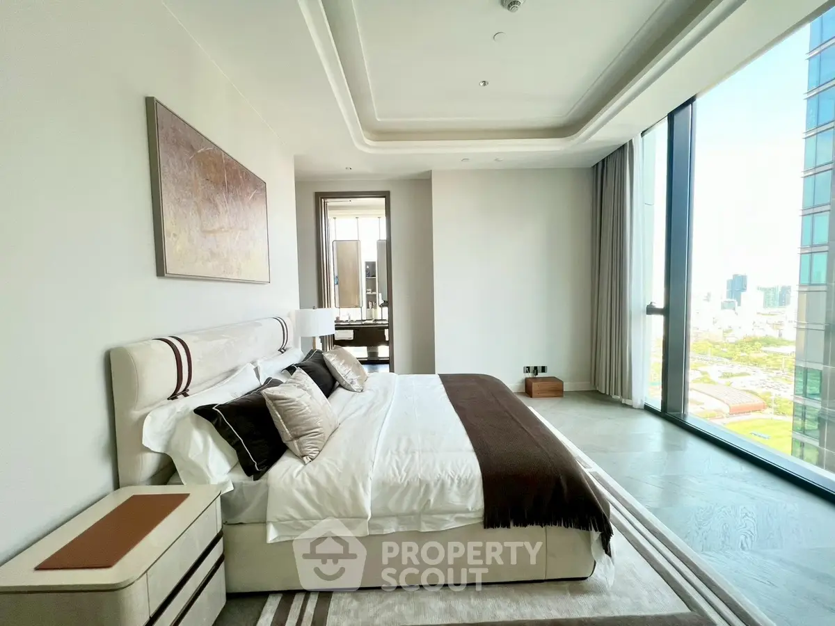 Luxurious bedroom with floor-to-ceiling windows offering stunning city views, modern decor, and elegant furnishings.
