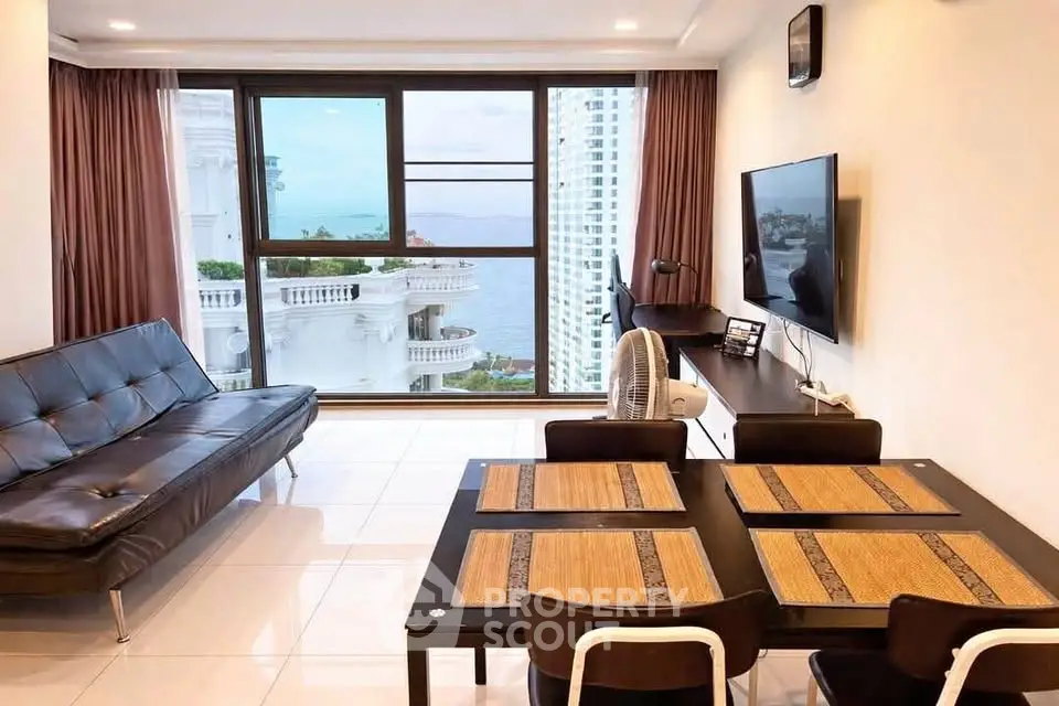 Modern living room with ocean view, sleek furniture, and large windows in a high-rise apartment.