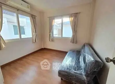 Bright room with large windows and a covered sofa, perfect for a cozy living space.
