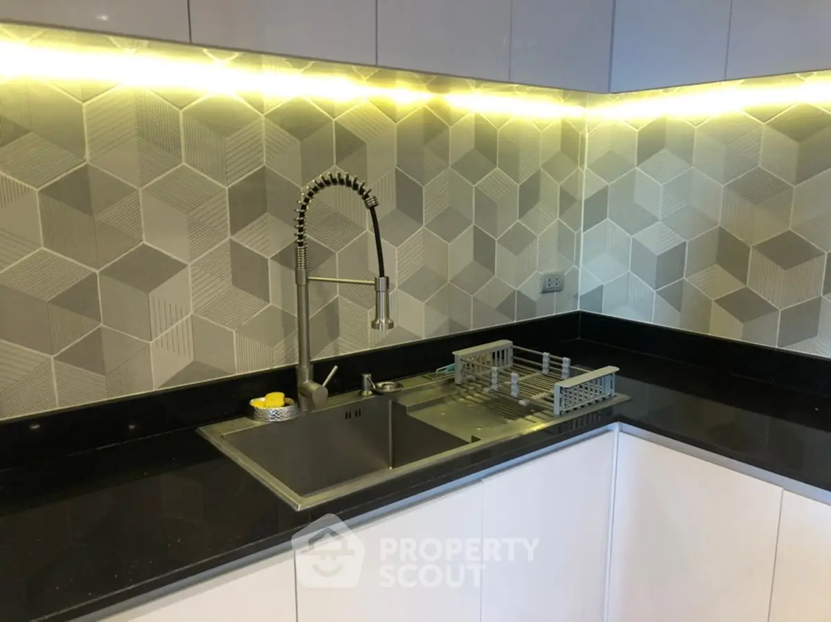 Modern kitchen with sleek black countertops and geometric backsplash design.