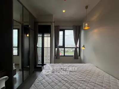 Modern bedroom with large windows and city view, featuring stylish lighting and cozy bedding.