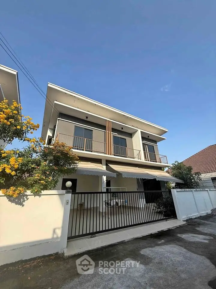 Modern two-story house with balcony and garden in a serene neighborhood.