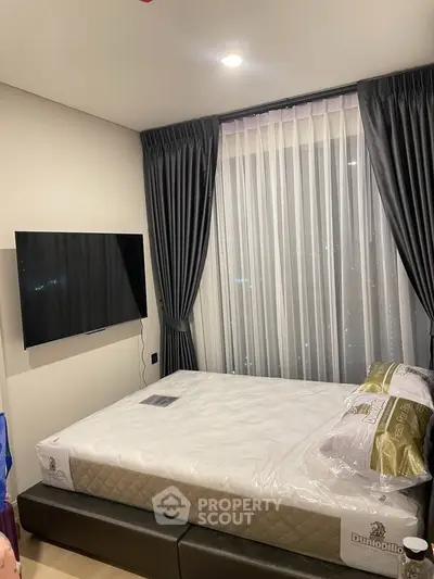 Modern bedroom with large window, stylish curtains, and wall-mounted TV in a contemporary apartment.