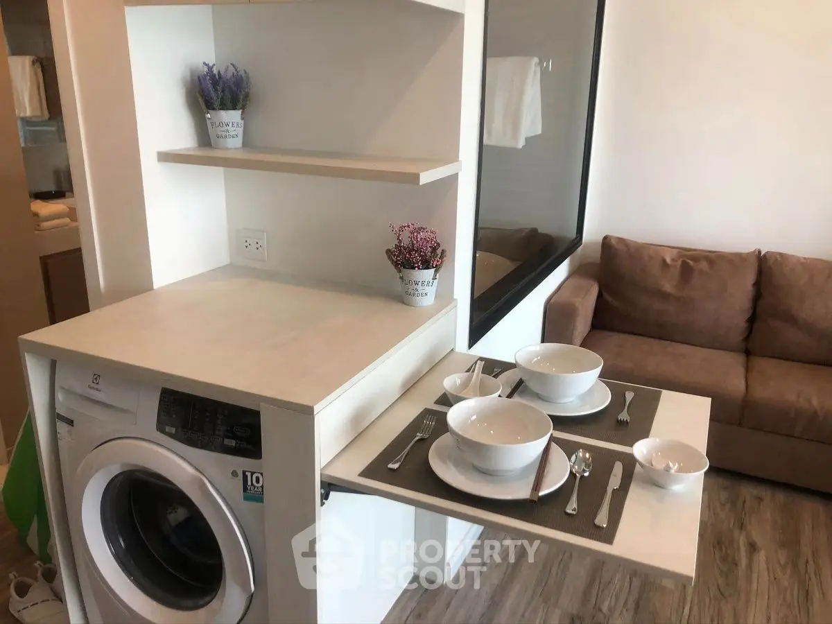 Compact living space with integrated washing machine and dining table, ideal for modern urban living.