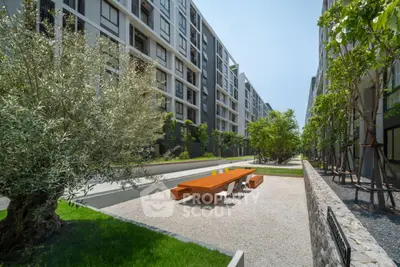 Modern apartment complex with landscaped garden and outdoor seating area.