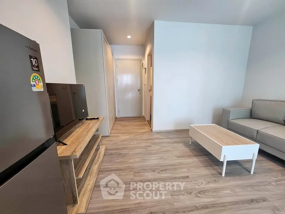 Modern living room with sleek furniture and wooden flooring, featuring a cozy sofa and entertainment unit.