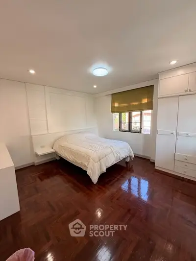 Spacious bedroom with wooden flooring and ample natural light