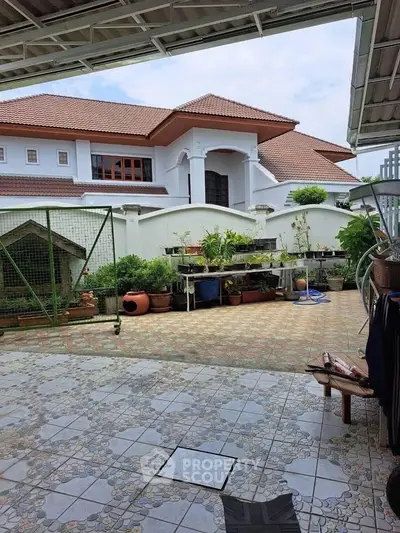 Spacious outdoor patio with tiled flooring and lush garden view in a luxurious residential property.