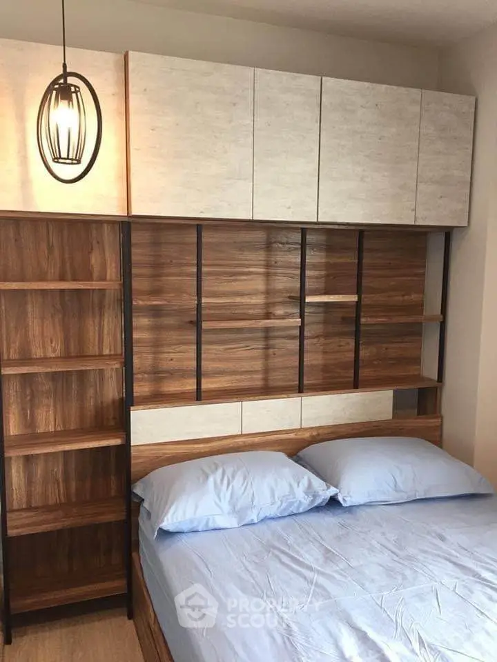 Modern bedroom with stylish wooden headboard and overhead storage cabinets.