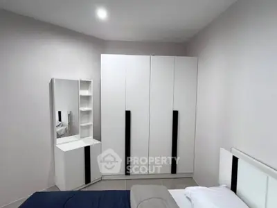 Modern bedroom with sleek white wardrobe and vanity set, showcasing minimalist design.