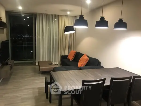 Modern living room with city view, stylish lighting, and cozy seating area.