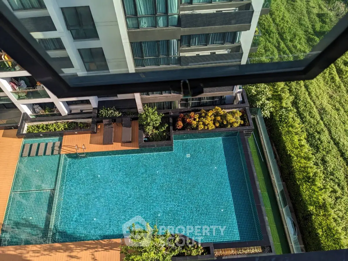 Stunning aerial view of modern apartment building with inviting swimming pool and lush greenery.