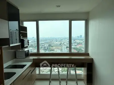 Modern kitchen with panoramic city view, featuring sleek countertops and built-in appliances.