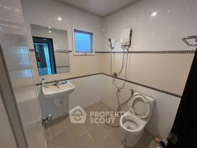 Modern bathroom with shower, toilet, and sink in a tiled interior.