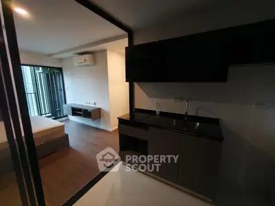 Modern studio apartment with sleek kitchenette and spacious bedroom, featuring contemporary design and natural light.