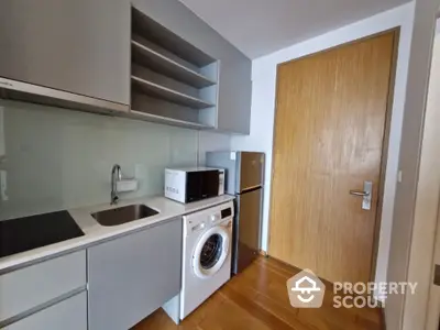 Modern compact kitchen with washing machine and microwave in sleek apartment