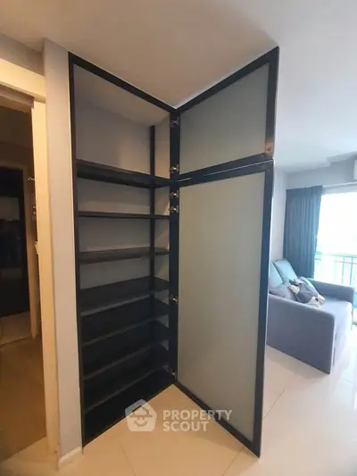 Modern apartment interior with sleek black shelving unit and cozy living area.