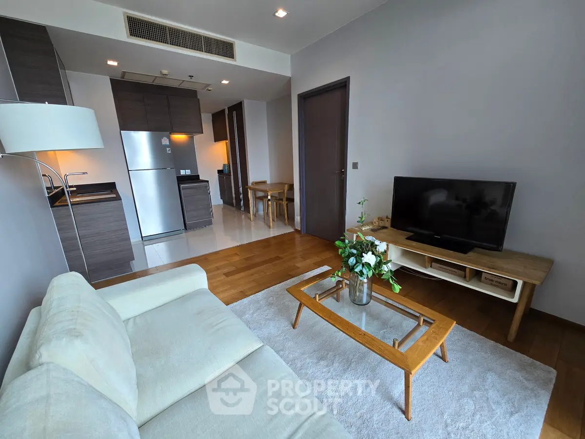 Modern living room with sleek kitchen, cozy sofa, and flat-screen TV in stylish apartment.