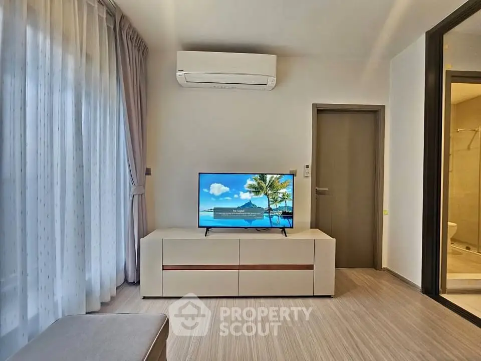 Modern living room with air conditioning and flat-screen TV, adjacent to a bathroom.