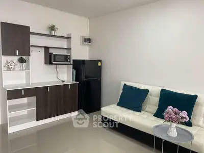 Modern studio apartment with sleek kitchenette and cozy seating area.