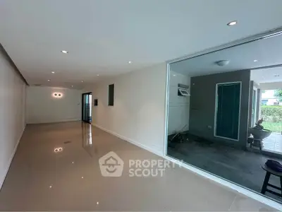 Spacious modern living room with sleek design and large glass doors opening to a patio area.