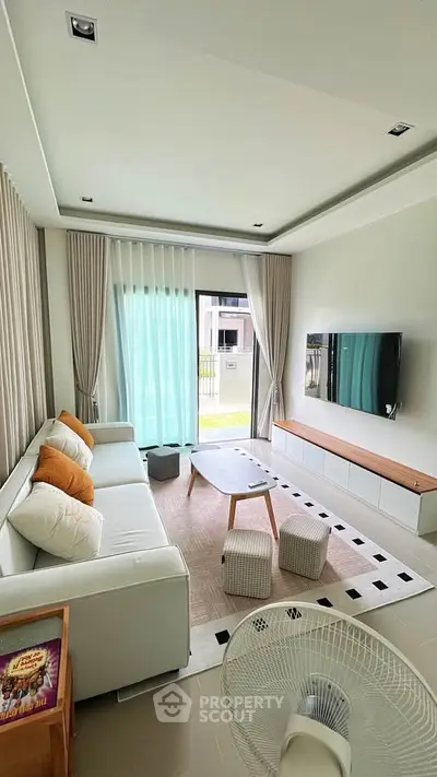 Modern living room with sleek furniture and large window offering natural light.