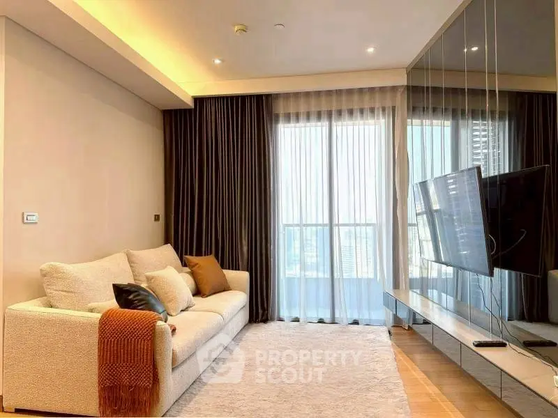 Modern living room with cozy sofa and large TV, featuring floor-to-ceiling windows and elegant curtains.