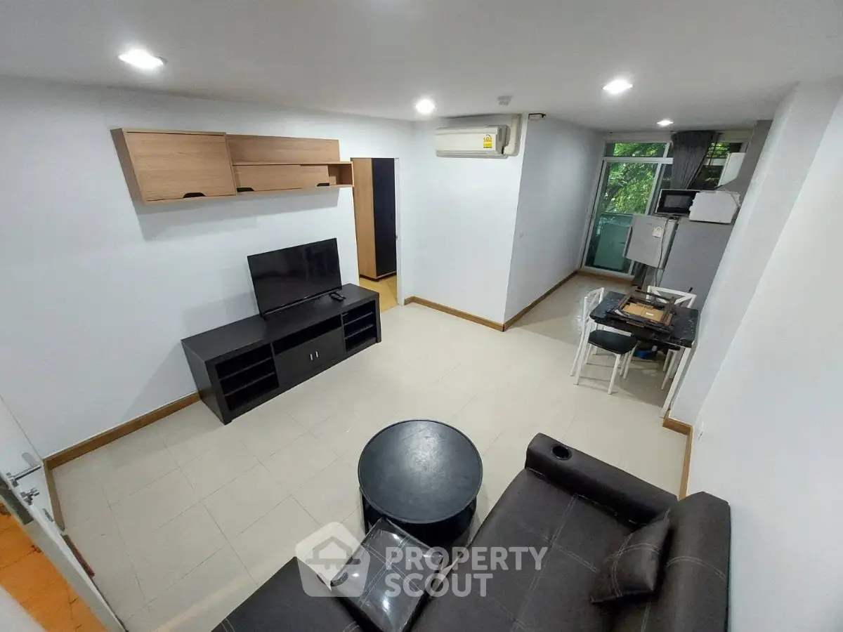 Modern living room with sleek furniture and natural light, featuring a cozy seating area and entertainment setup.