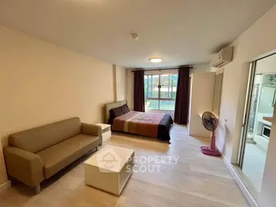 Spacious studio apartment with modern furnishings and large window for natural light.