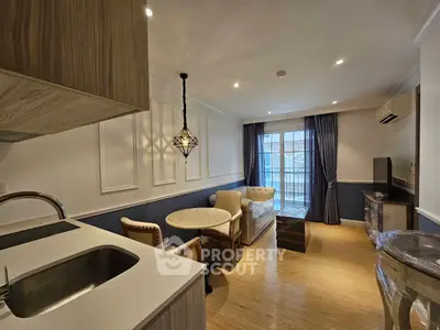 Chic modern living room with open kitchen and elegant decor, featuring a cozy seating area and stylish lighting.