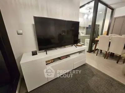 Modern living room with sleek TV setup and dining area in open layout apartment.